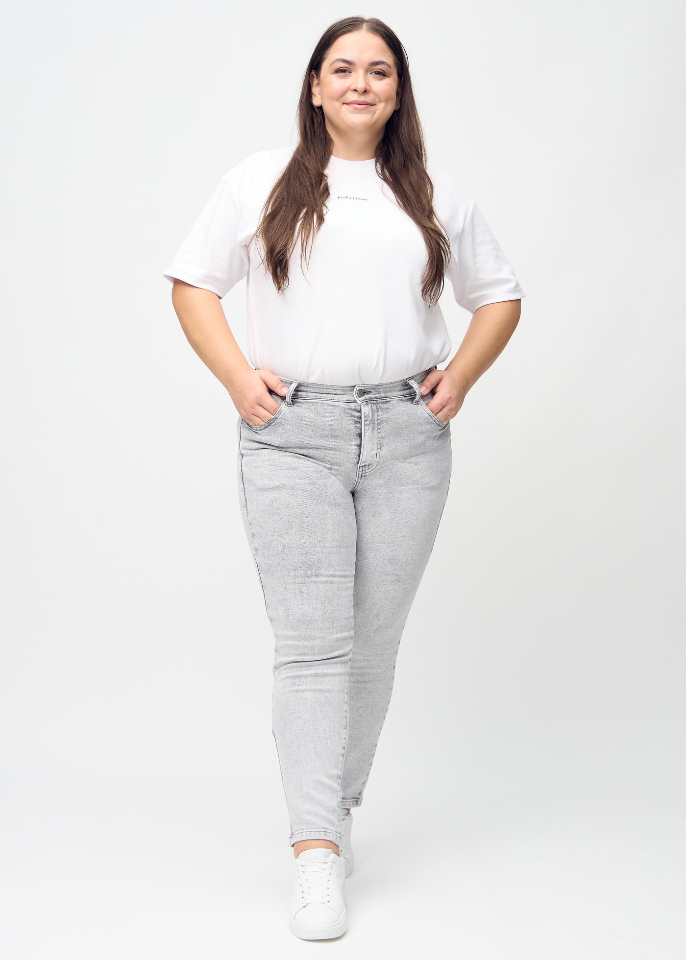 Fuldt billede af en plus-size model i lysegrå denim slim jeans.