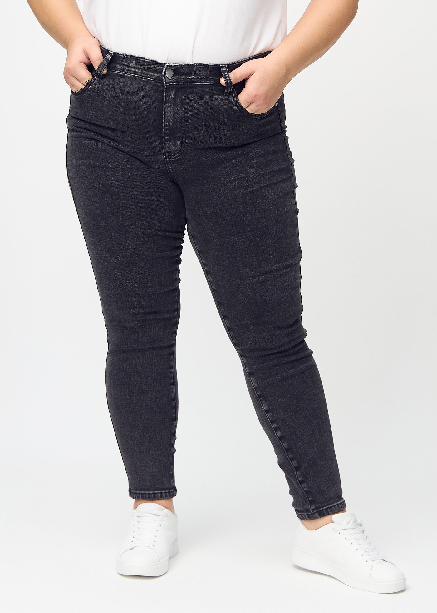 Mørkegrå denim skinny jeans, modelnavn Shadows, som sidder tæt til benet på en plus-size model, set forfra.