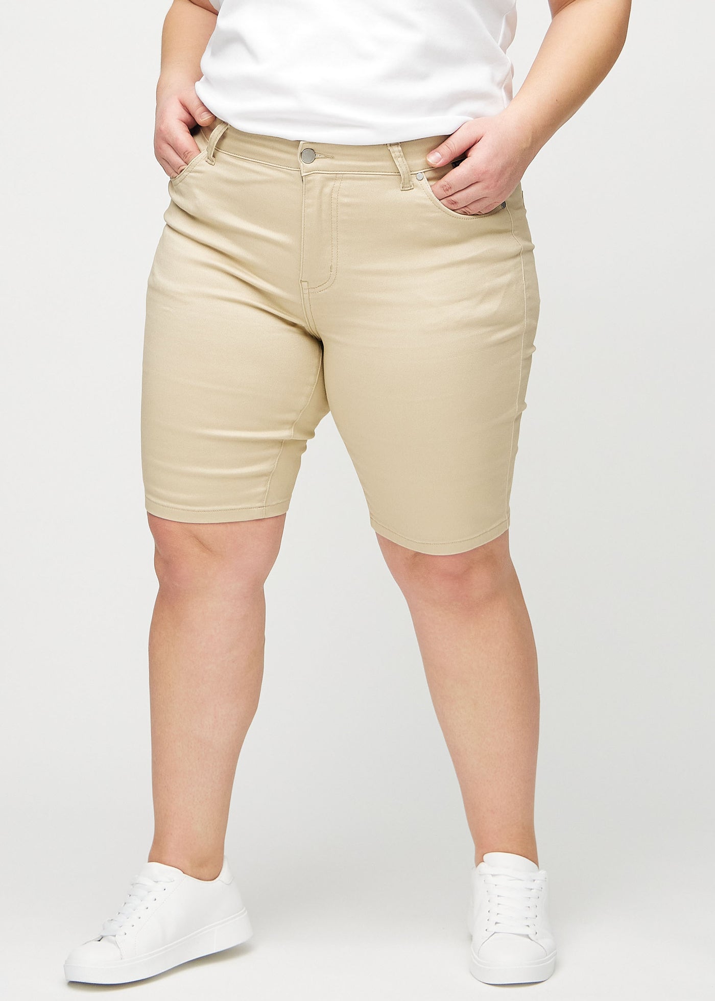 Beige skinny middle shorts, modelnavn Gazelles, som sidder tæt til låret og slutter lige over knæet på en plus-size model, set forfra.