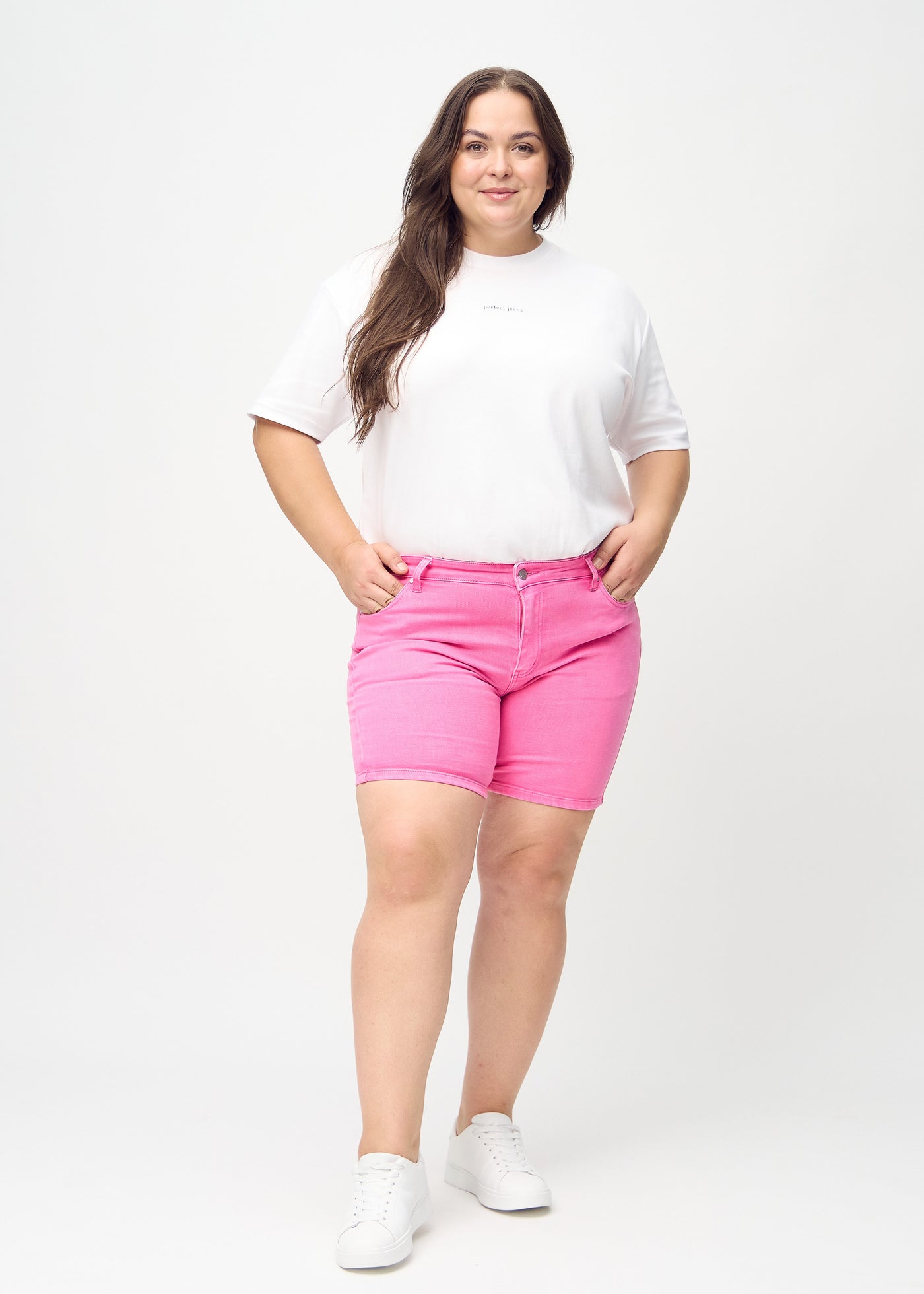 Fuldt billede af en plus-size model i lyserøde skinny short shorts.