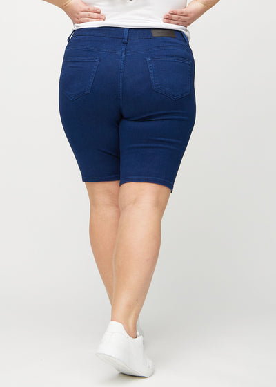 Mørkeblå skinny middle shorts set bagfra på en plus-size model, så man kan se hele produktet.