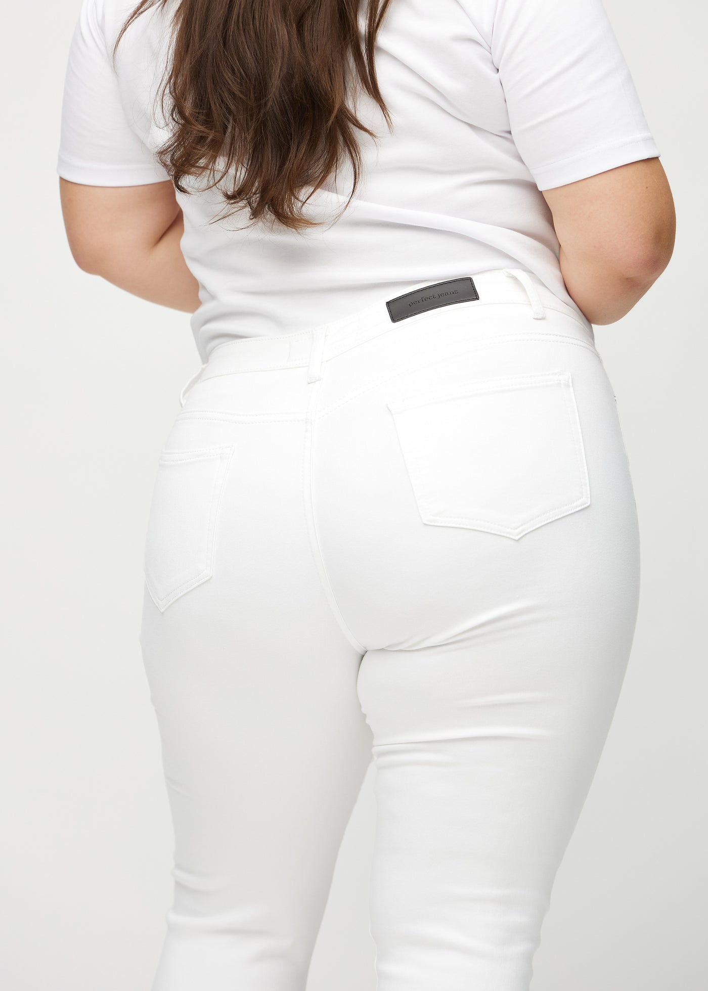 Hvide skinny capris set bagfra tæt på en plus-size model for at vise detaljer.