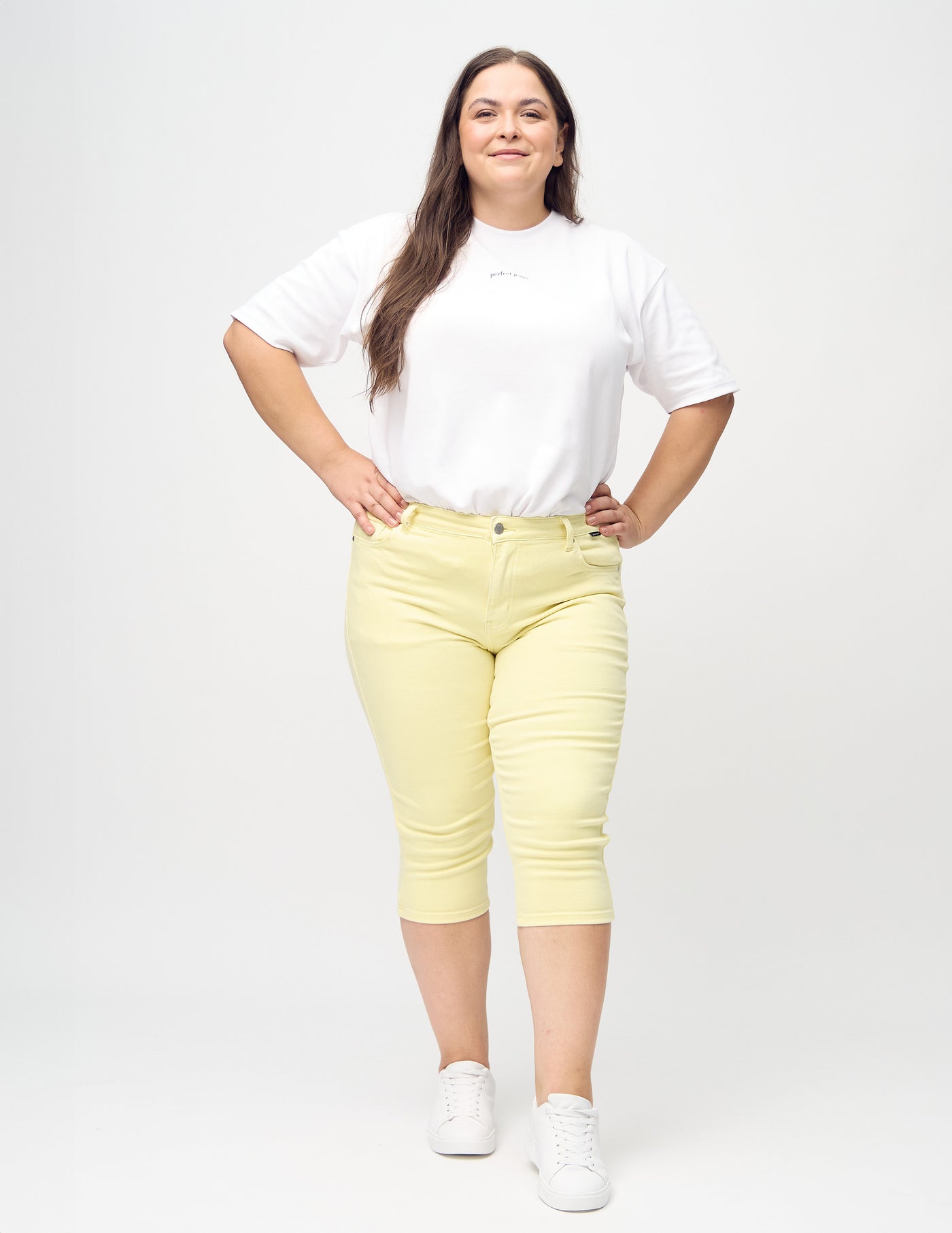 Fuldt billede af en plus-size model i lysegule skinny capris.