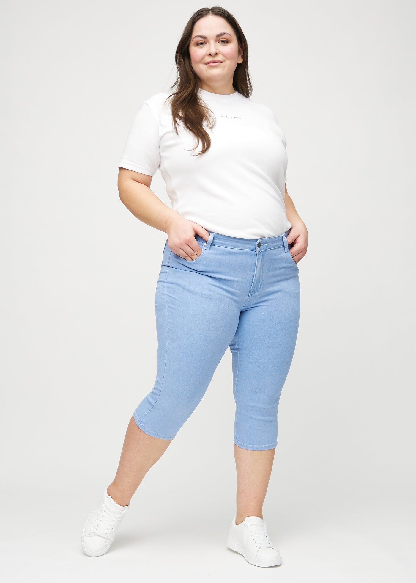 Fuldt billede af en plus-size model i lyseblå skinny capris.