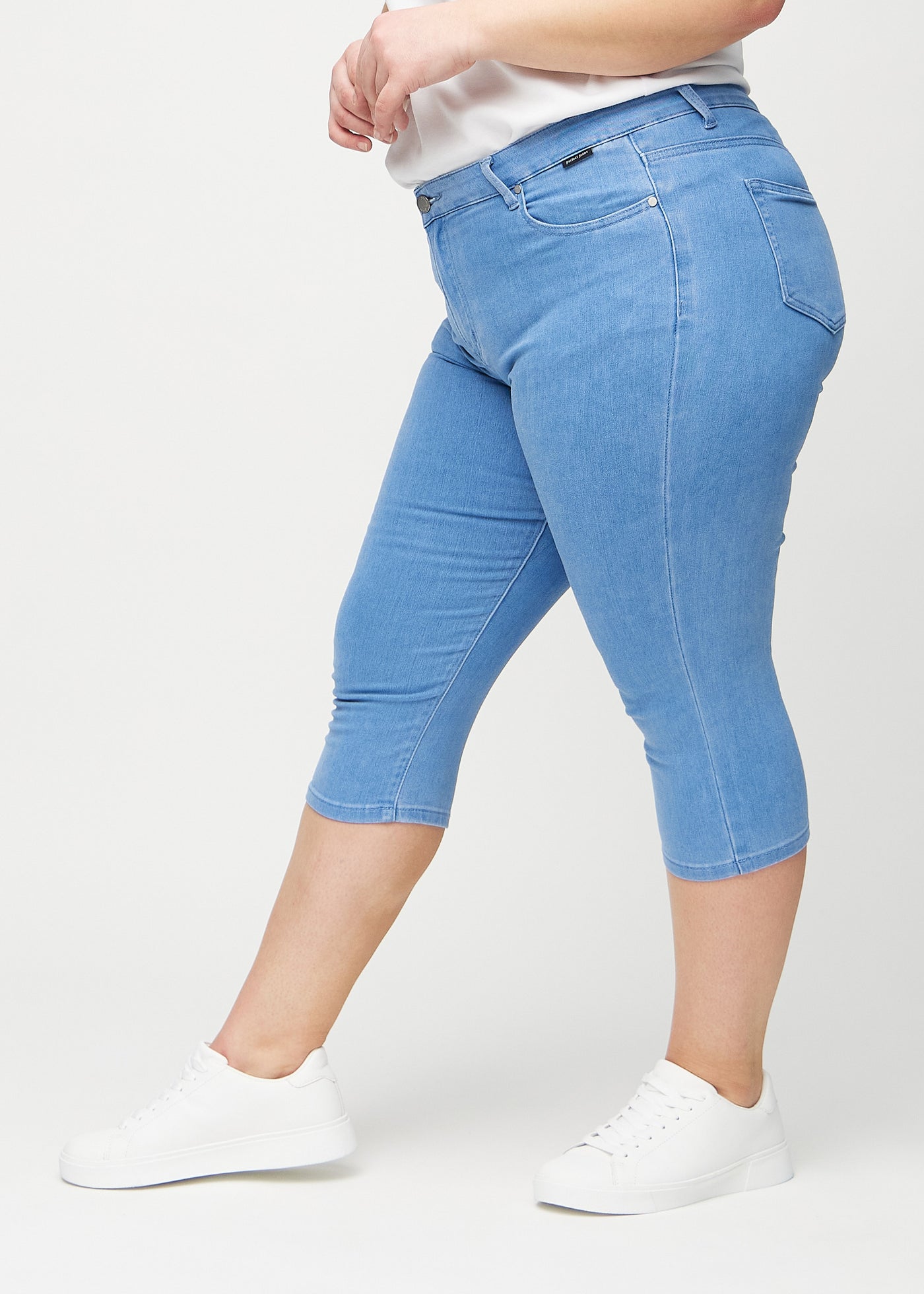 Blå skinny capris set fra siden på en plus-size model.