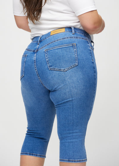 Denim skinny capris set bagfra tæt på en plus-size model for at vise detaljer.