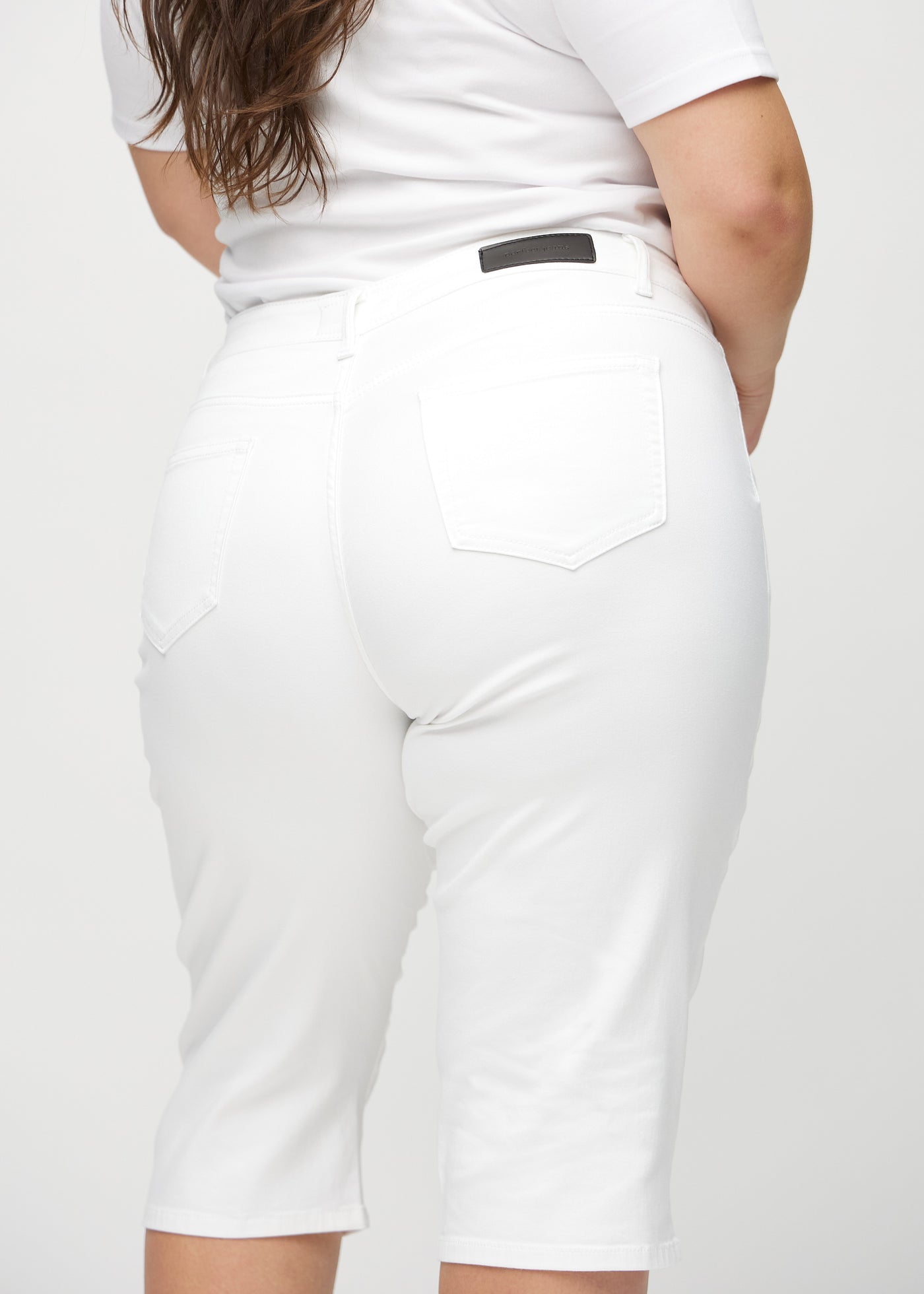 Hvide regular capris set bagfra tæt på en plus-size model for at vise detaljer.