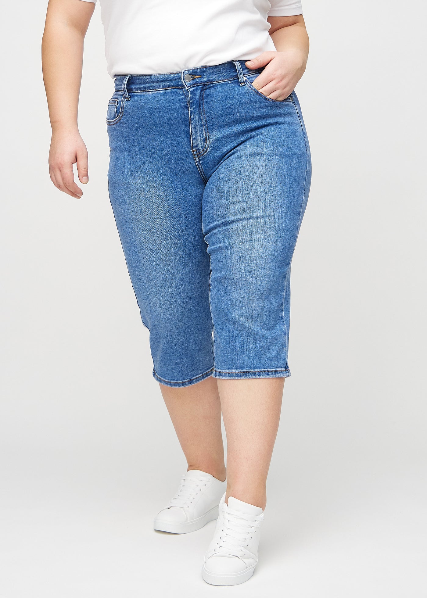 Denim regular capris, modelnavn Rivers, som sidder lige til benet og slutter lige under knæet på en plus-size model, set forfra.