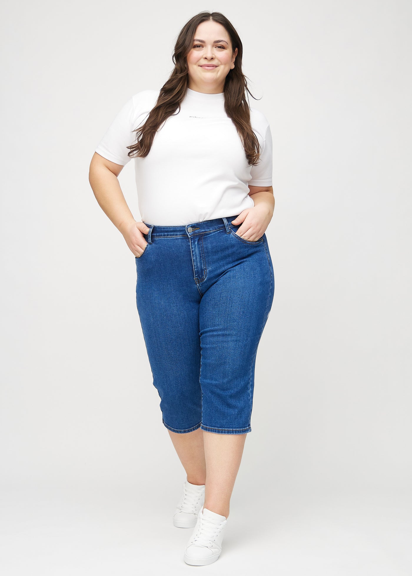 Fuldt billede af en plus-size model i mørk denim regular capris.