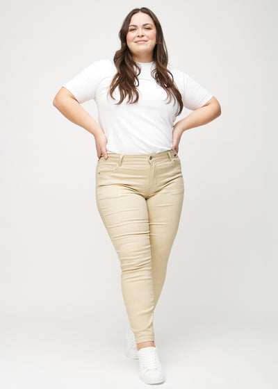 Fuldt billede af en plus-size model i beige skinny jeans.