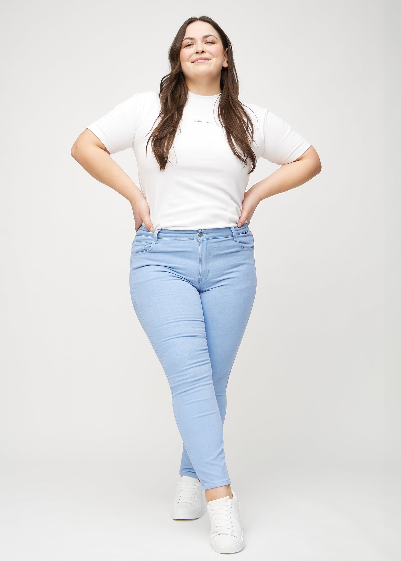 Fuldt billede af en plus-size model i lyseblå skinny jeans.