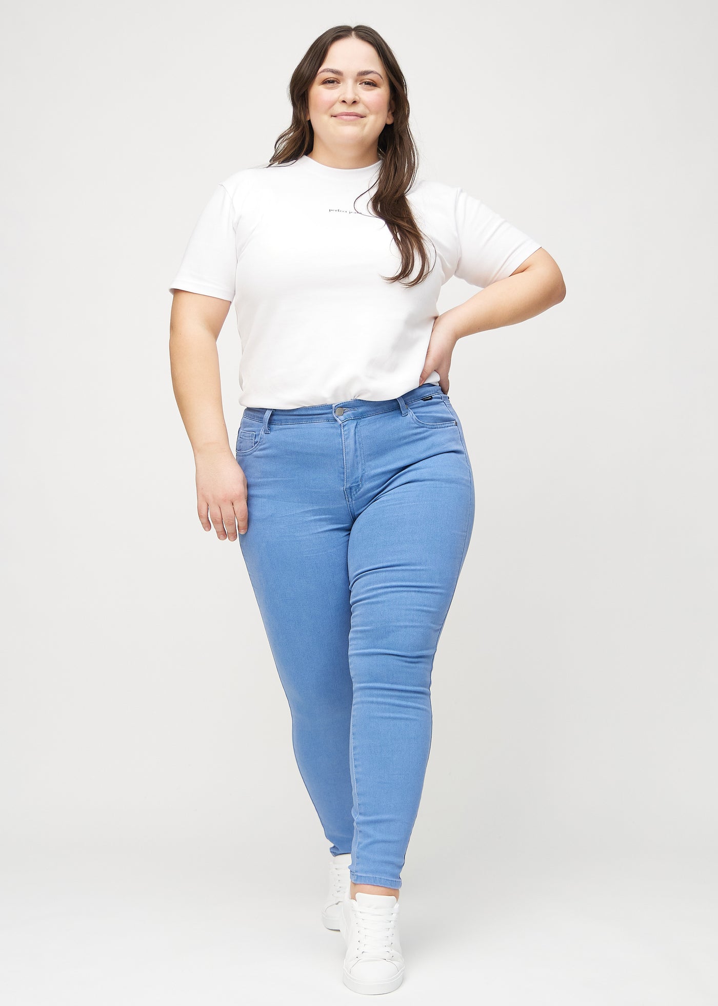 Fuldt billede af en plus-size model i blå skinny jeans.