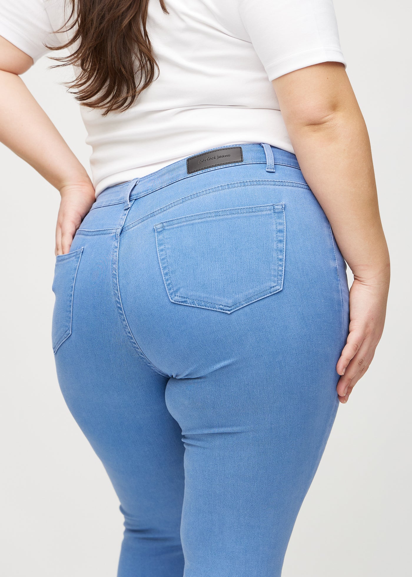 Blå skinny jeans set bagfra tæt på en plus-size model for at vise detaljer.