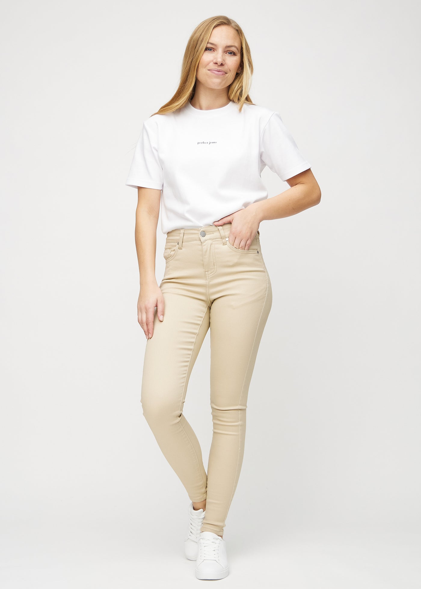 Fuldt billede af model i beige skinny jeans.