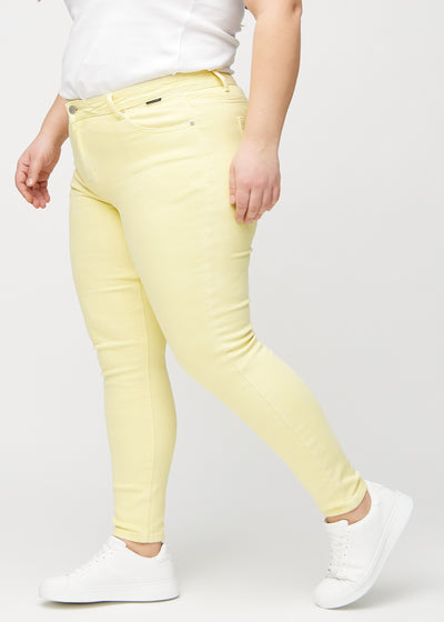 Lysegule skinny jeans set fra siden på en plus-size model.