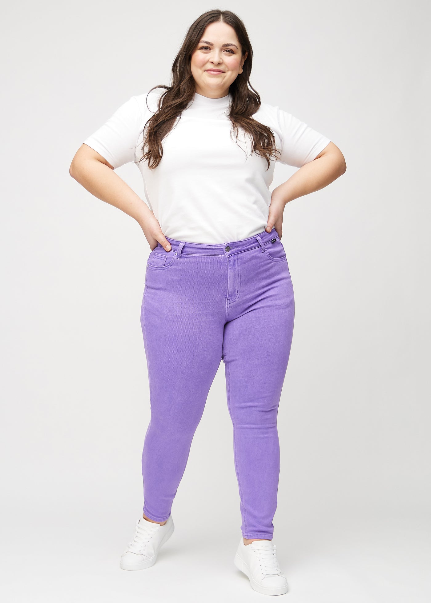 Fuldt billede af en plus-size model i lilla skinny jeans.