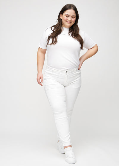 Fuldt billede af en plus-size model i hvide slim jeans.