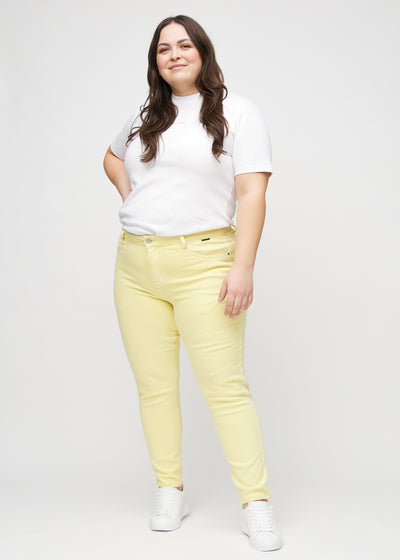 Fuldt billede af en plus-size model i lysegule slim jeans.