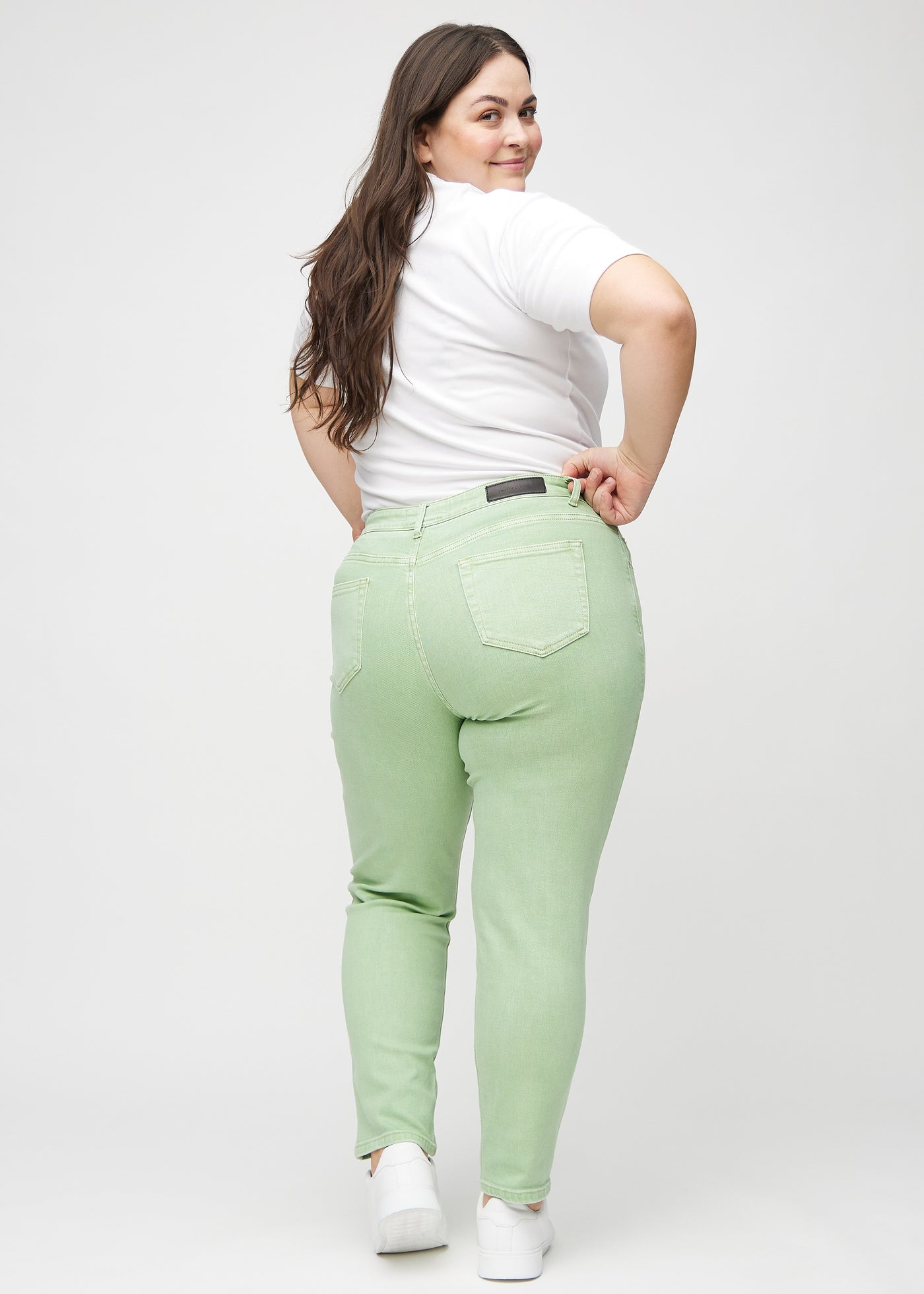 Lysegrønne slim jeans set bagfra på en plus-size model, så man kan se hele produktet.