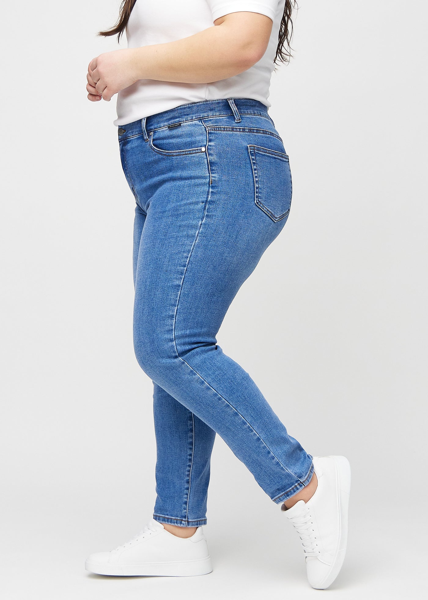 Denim slim jeans set fra siden på en plus-size model.