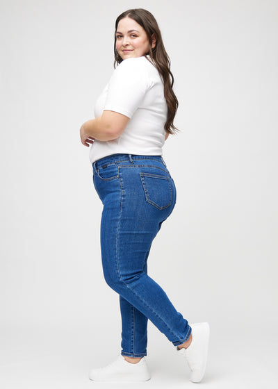 Mørk denim slim ultra high rise jeans set fra siden på en plus-size model.