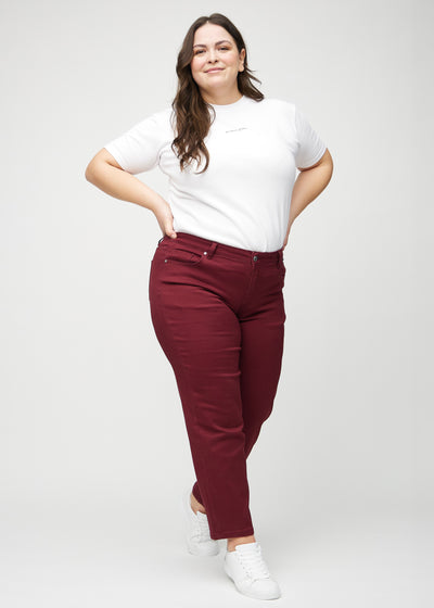 Fuldt billede af en plus-size model i mørkerøde regular jeans.