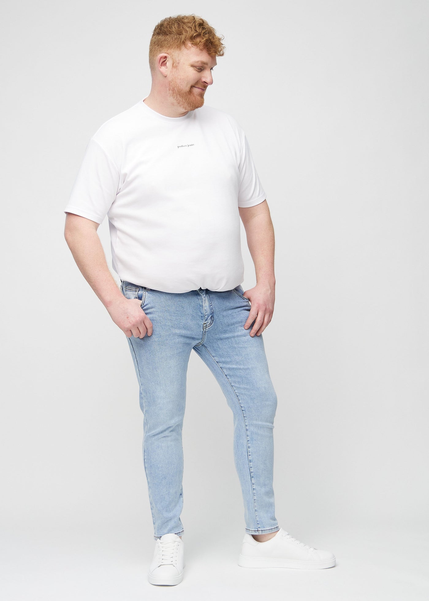 Fuldt billede af en plus-size model i lys denim slim jeans.