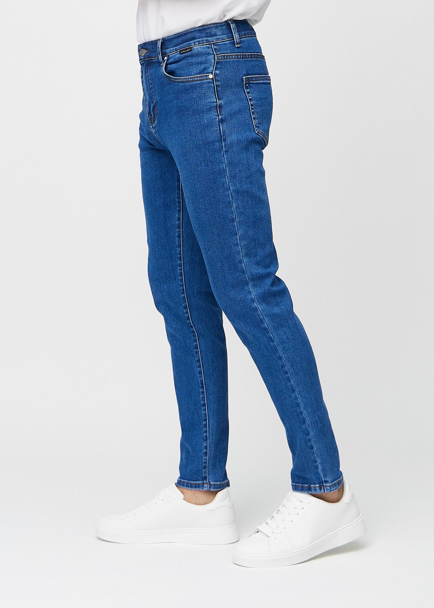 Mørk denim slim jeans set fra siden på model.