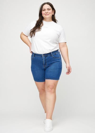 Plus-size model går ind i billedet, strækker i sine shorts, viser dem frem ved at dreje rundt, og forlader derefter billedet.