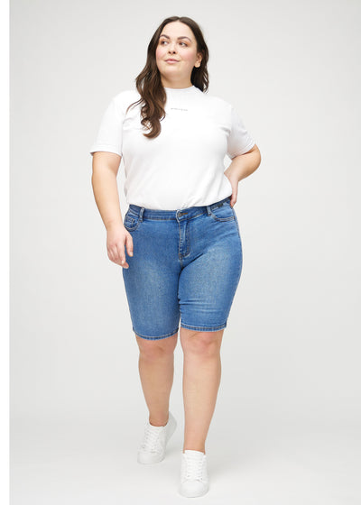 Plus-size model går ind i billedet, strækker i sine shorts, viser dem frem ved at dreje rundt, og forlader derefter billedet.