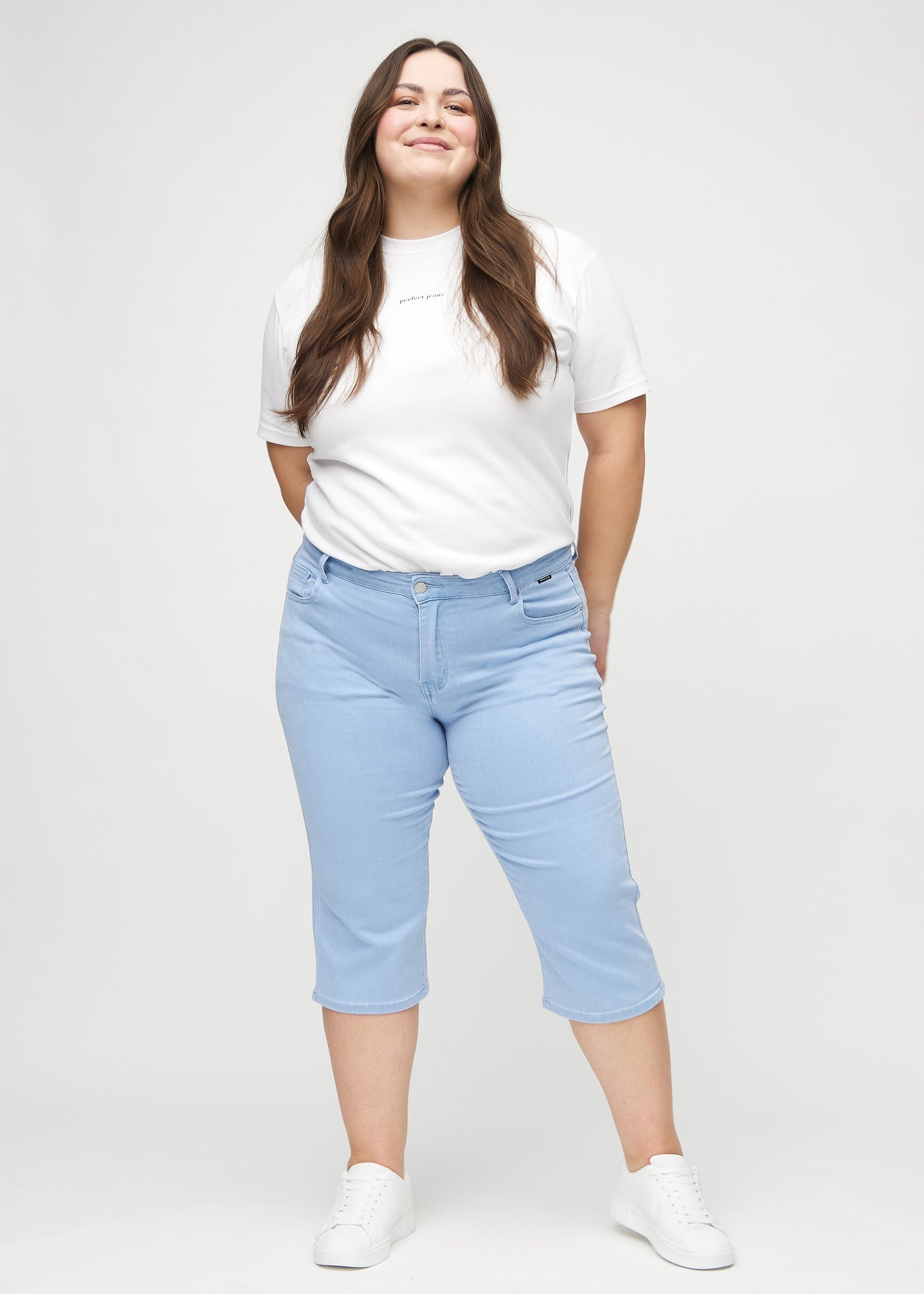 Plus-size model går ind i billedet, strækker i sine capris, viser dem frem ved at dreje rundt, og forlader derefter billedet.