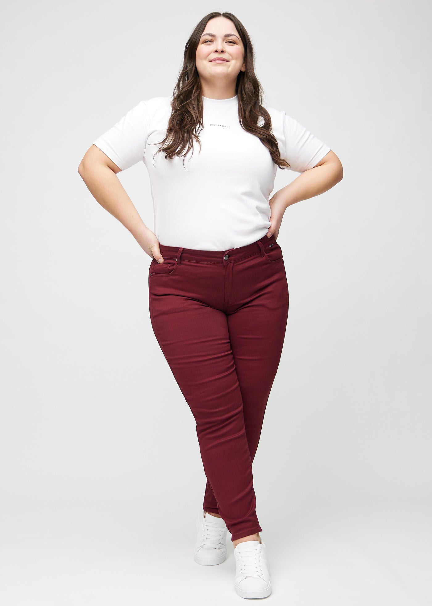 Plus-size model går ind i billedet, strækker i jeansene, viser dem frem ved at dreje rundt, og forlader derefter billedet.