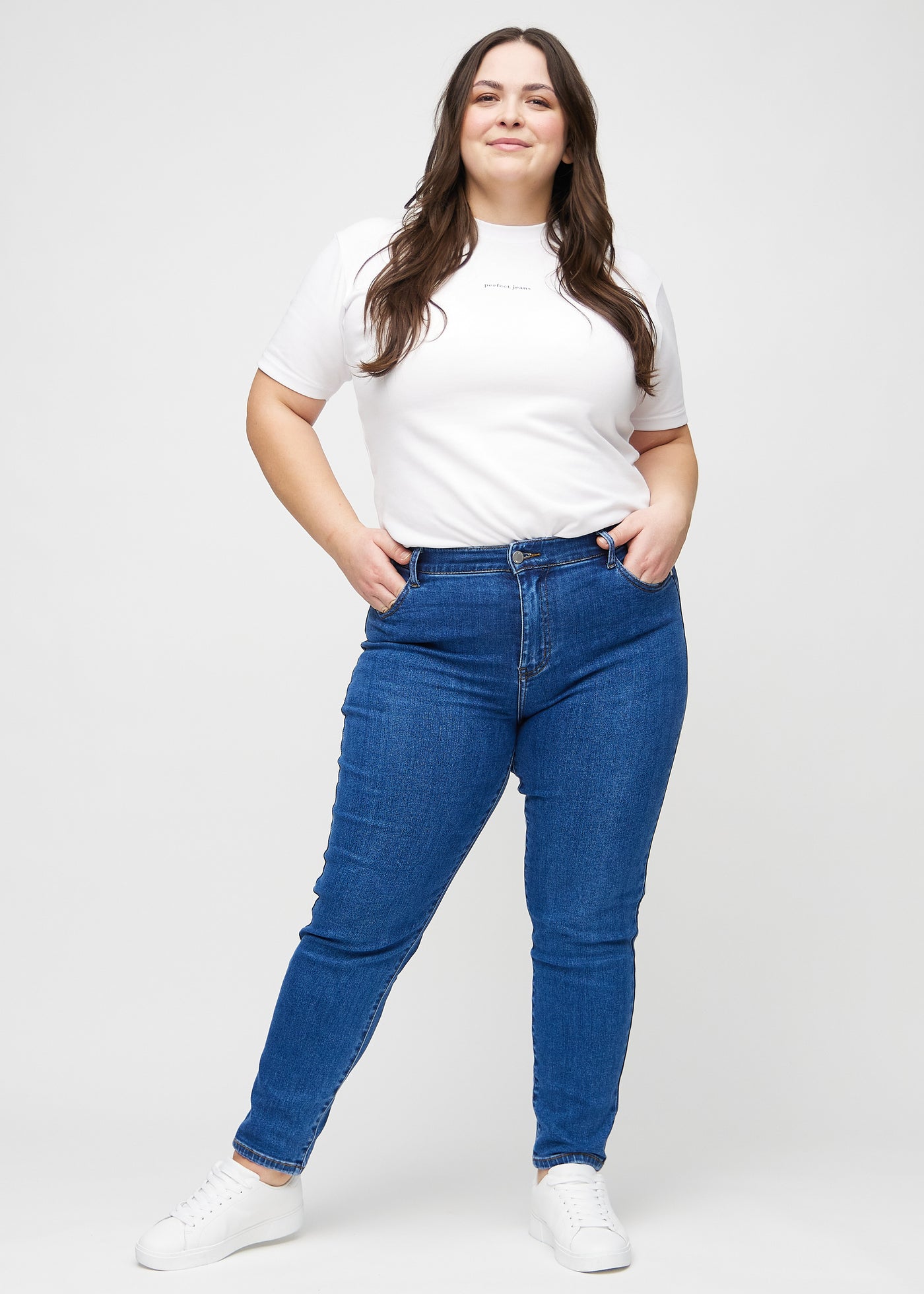 Plus-size model går ind i billedet, strækker i sine jeans, viser dem frem ved at dreje rundt, og forlader derefter billedet.